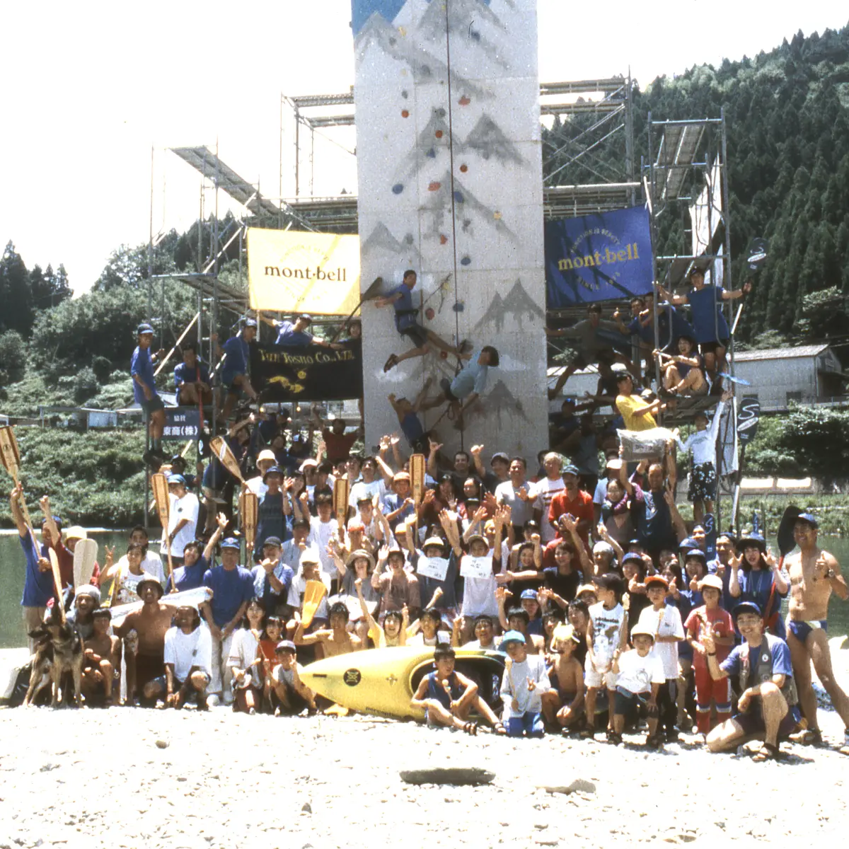 Group photo of people gathered in front of an outdoor climbing wall at the Montbell Summer Festival held in the Yoshino River basin in Shikoku