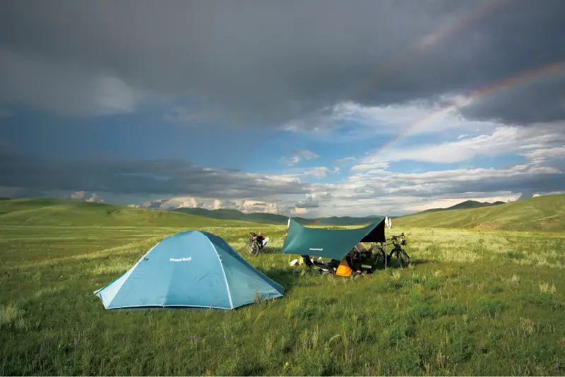 Tents and tarps set up in the meadow
