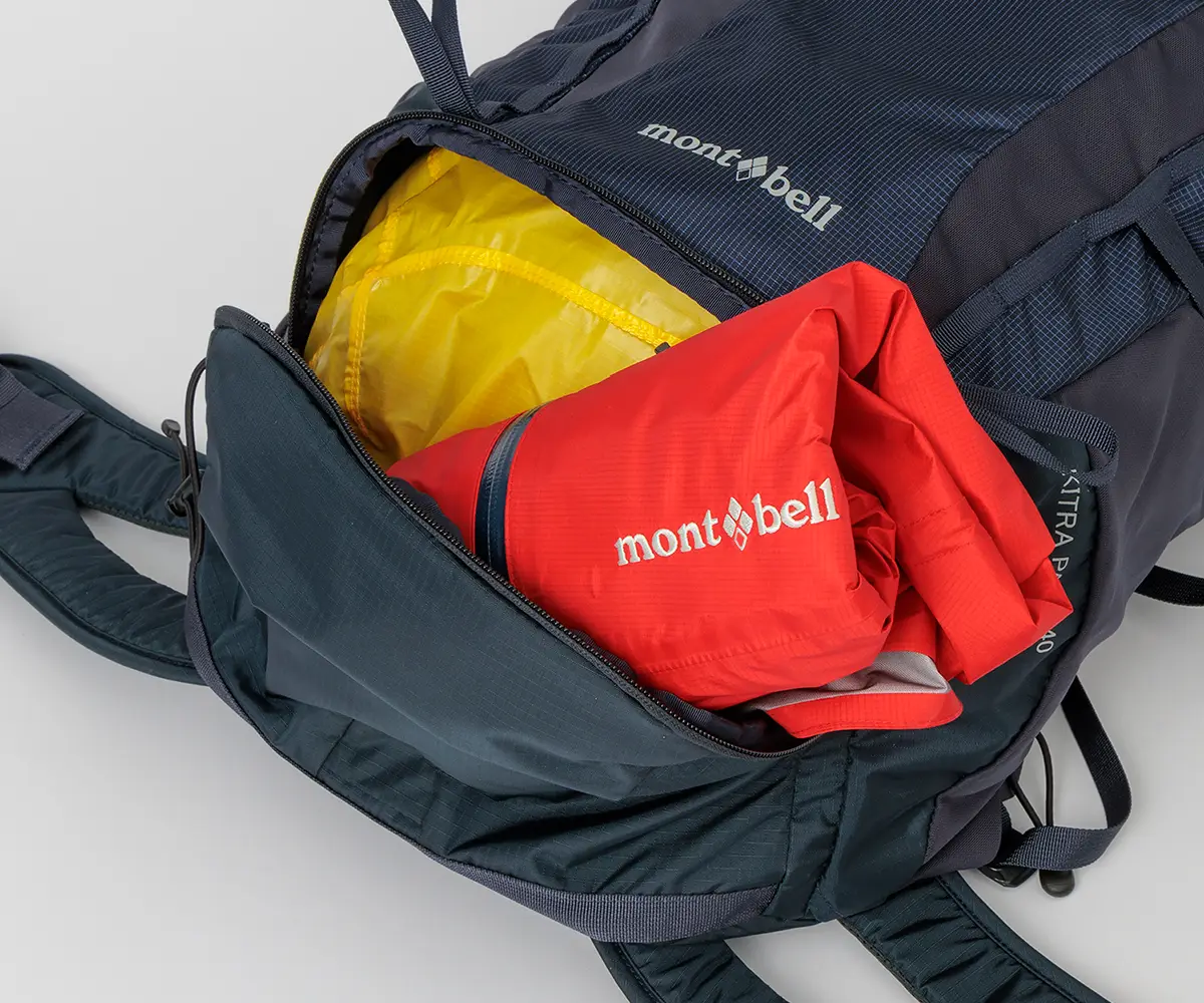 Storing a rain jacket through the bottom access of the Kitora Pack