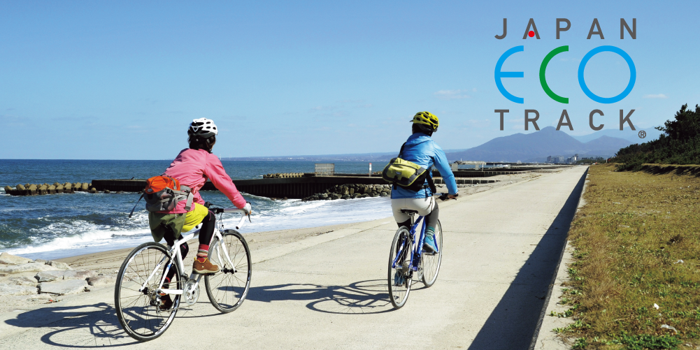 A view of two people riding bicycles along the coastline.