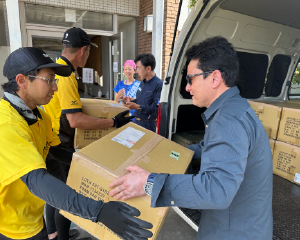 Mr. Noguchi receiving cardboard boxes from a volunteer and loading them into the vehicle.