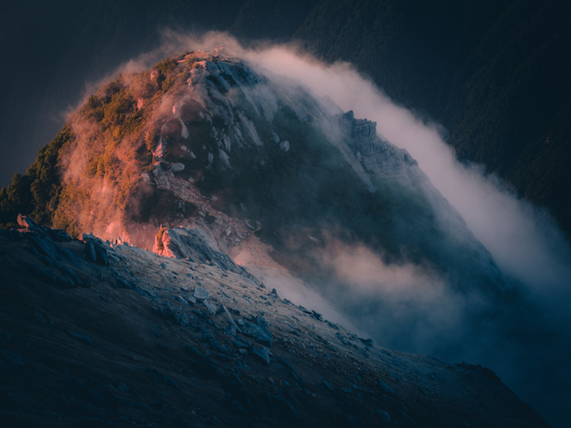 Mount Kaikoma at dawn. The western side of the mountain is dyed red as it receives the morning sun, while the eastern side remains dark and shadowed, not yet reached by the sunlight.
