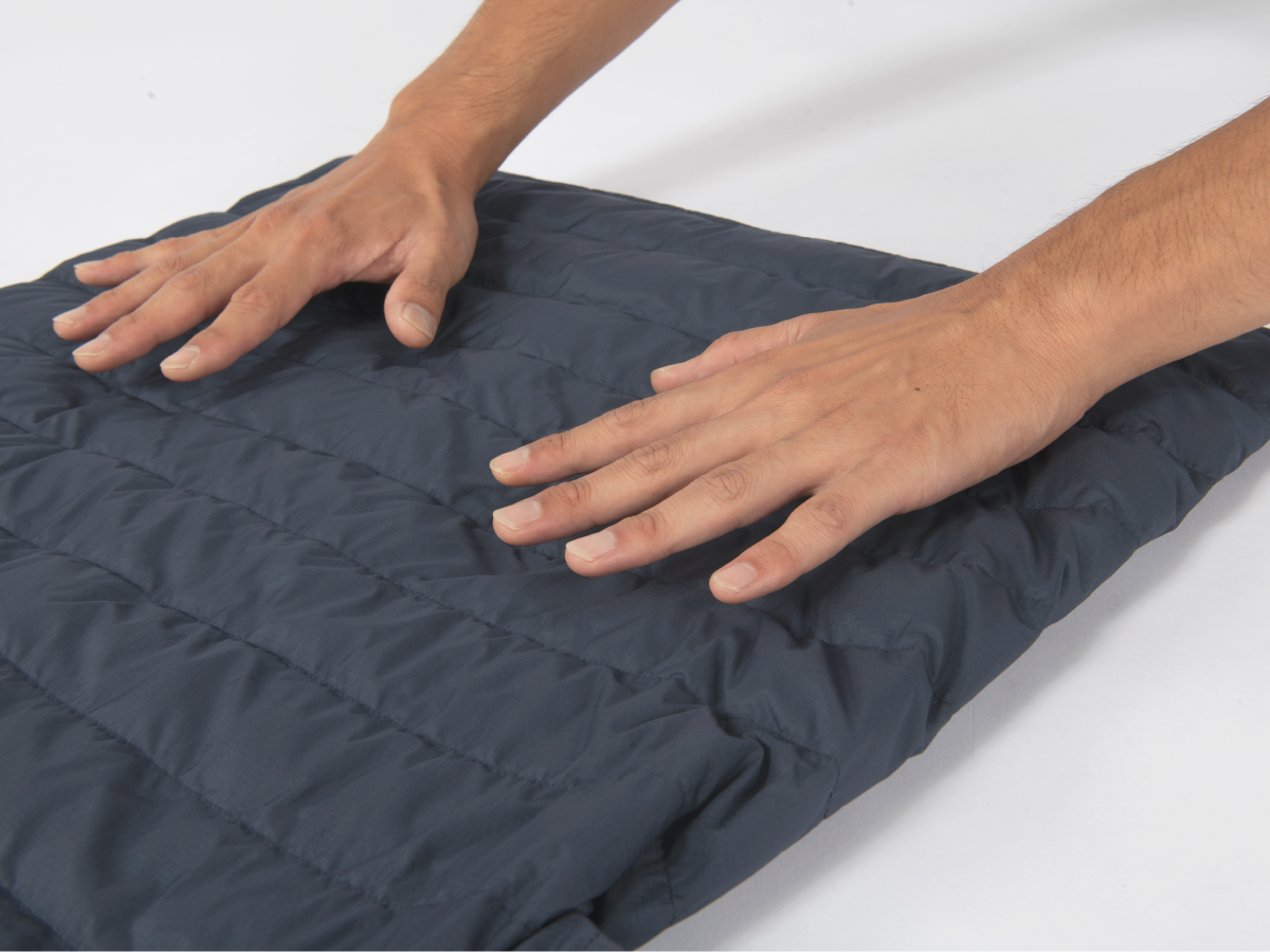 Gently patting the back of down outerwear laid flat with the palm of the hand