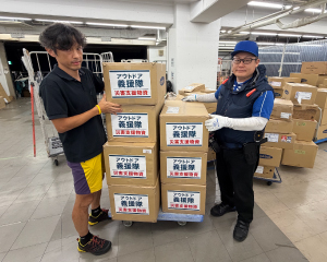 An Outdoor Gientai staff member handing over relief supplies to a logistics worker.