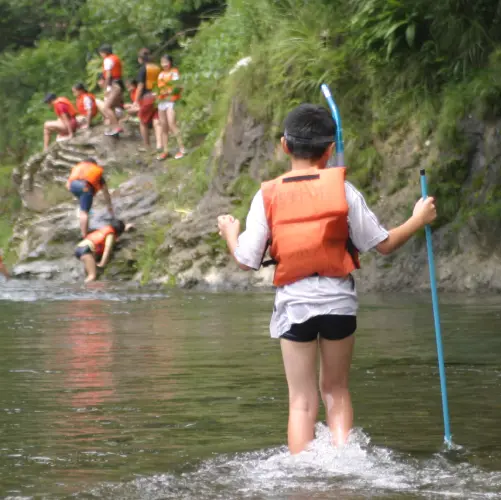 Children wearing life jackets are playing in the river.