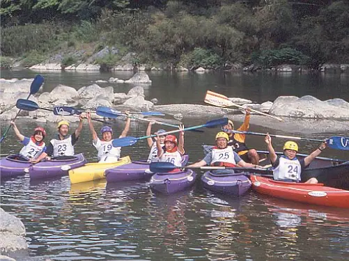 A group photo of several people experiencing kayaking. They are posing with their hands raised.