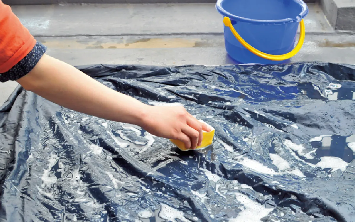 The base of the tent is being cleaned with a sponge.