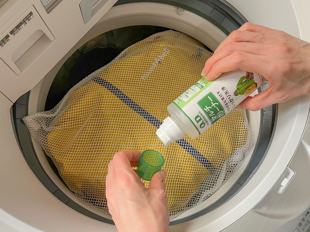 Image of washing a jacket in the washing machine. A multi-purpose cleaner removes dirt and oil from rainwear.