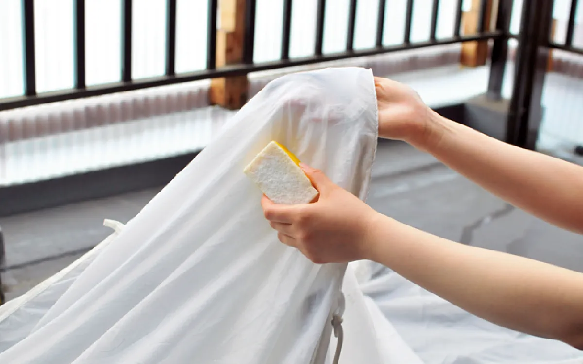 Both sides of the canopy (the mesh part of the main body and the top of the tent) are being cleaned with a sponge.