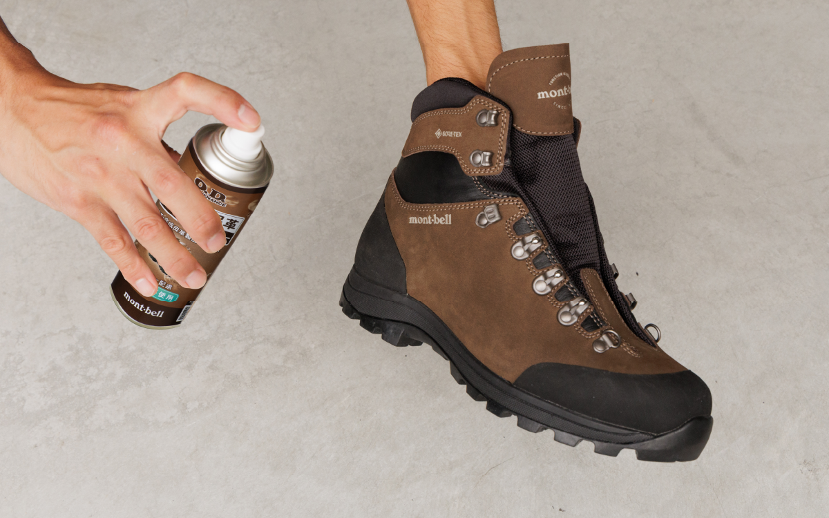 A scene showing the application of a spray-type waterproofing agent containing leather conditioner to leather hiking boots.