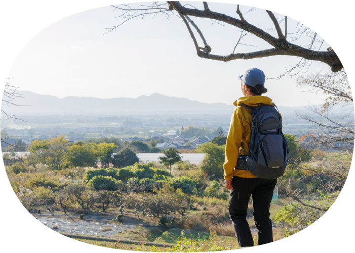 A woman gazing out from a high vantage point at a peaceful rural landscape. It evokes the image of a leisurely trip.
