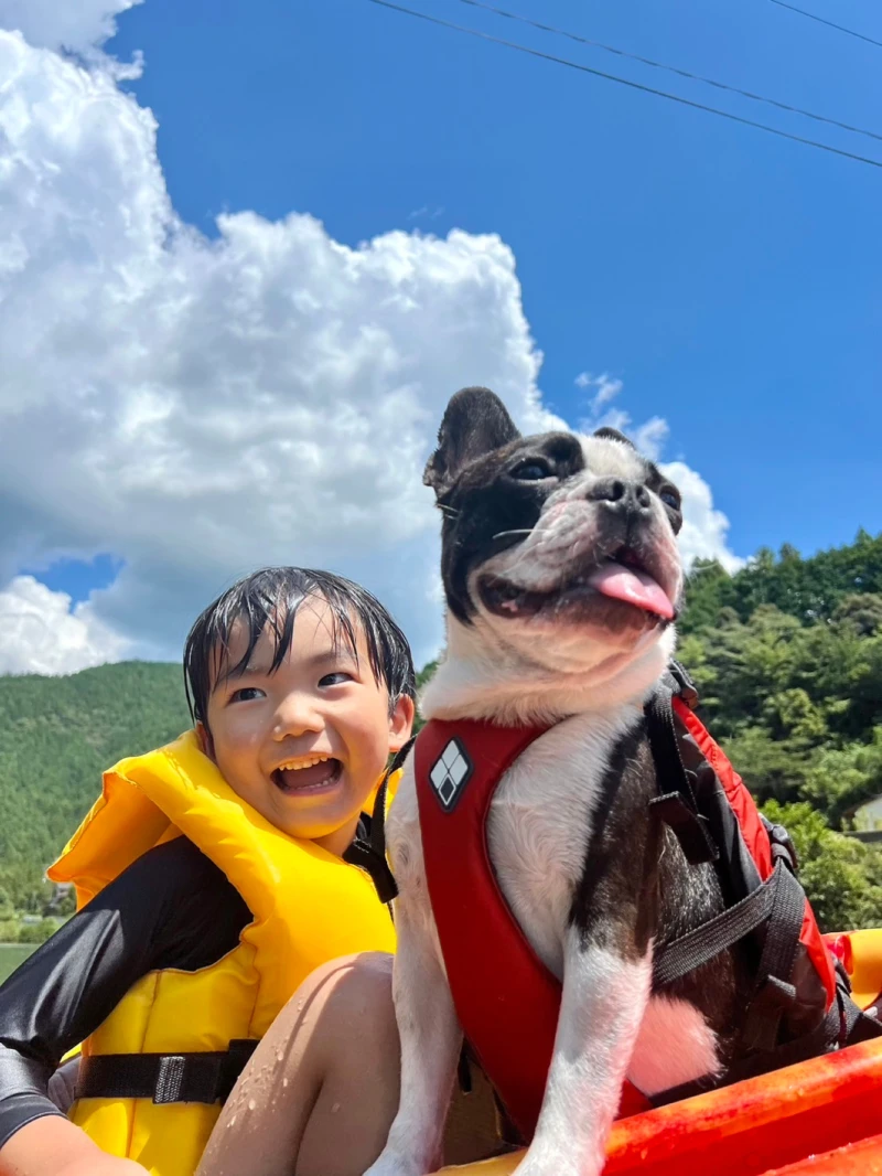 A child and a dog sitting close together on a kayak under clear skies