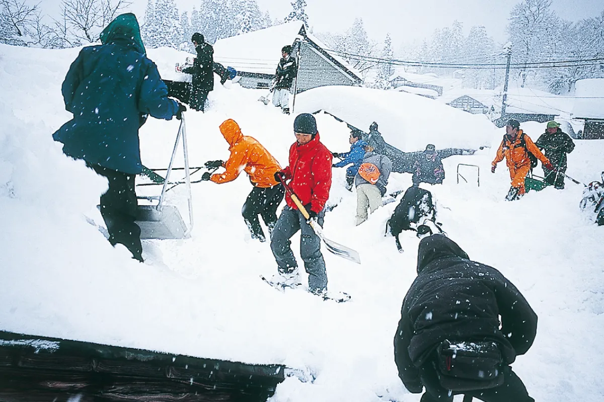 People removing snow from roofs to prevent house collapses due to the weight of snow accumulation.