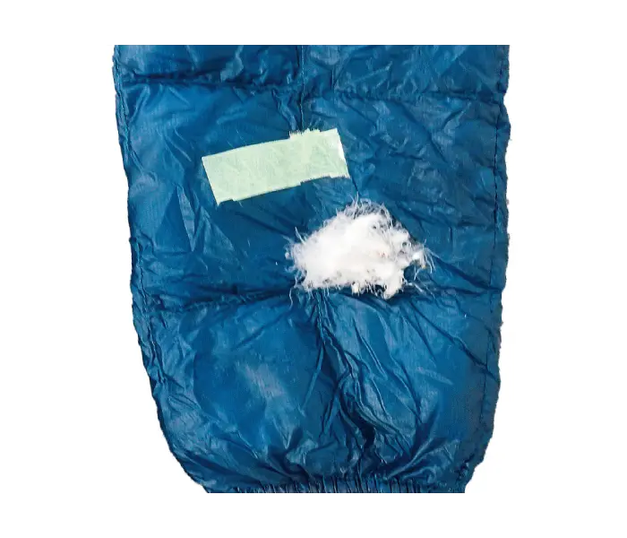 Down jacket before repair: Down feathers protruding from large tears in the fabric.