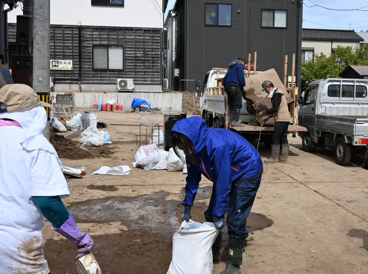 Outdoor Gientai staff removing debris. Trucks loaded with debris are parked around them.