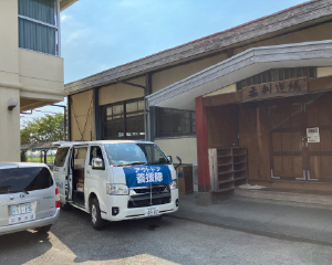 A vehicle loaded with relief supplies parked in front of a junior high school martial arts hall.
