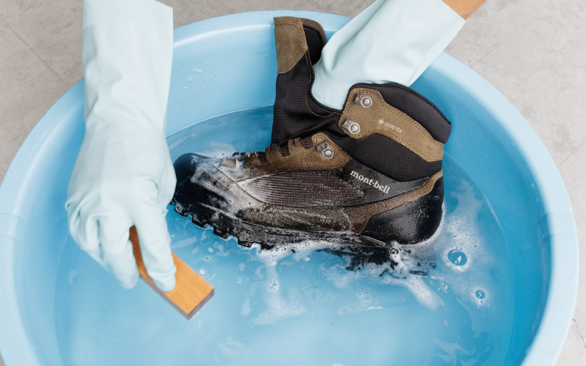 A scene depicting the process of submerging shoes in water and using a sponge to remove dirt.
