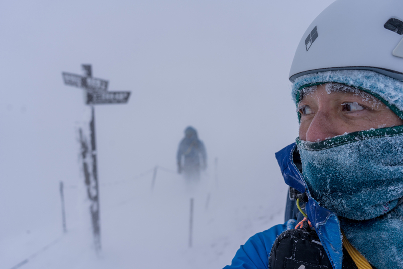 In a world blanketed in white snow, a man walks deeper into the scene. In the foreground, another man turns his back on him, choosing the opposite path, yet appears concerned about what lies behind him.
